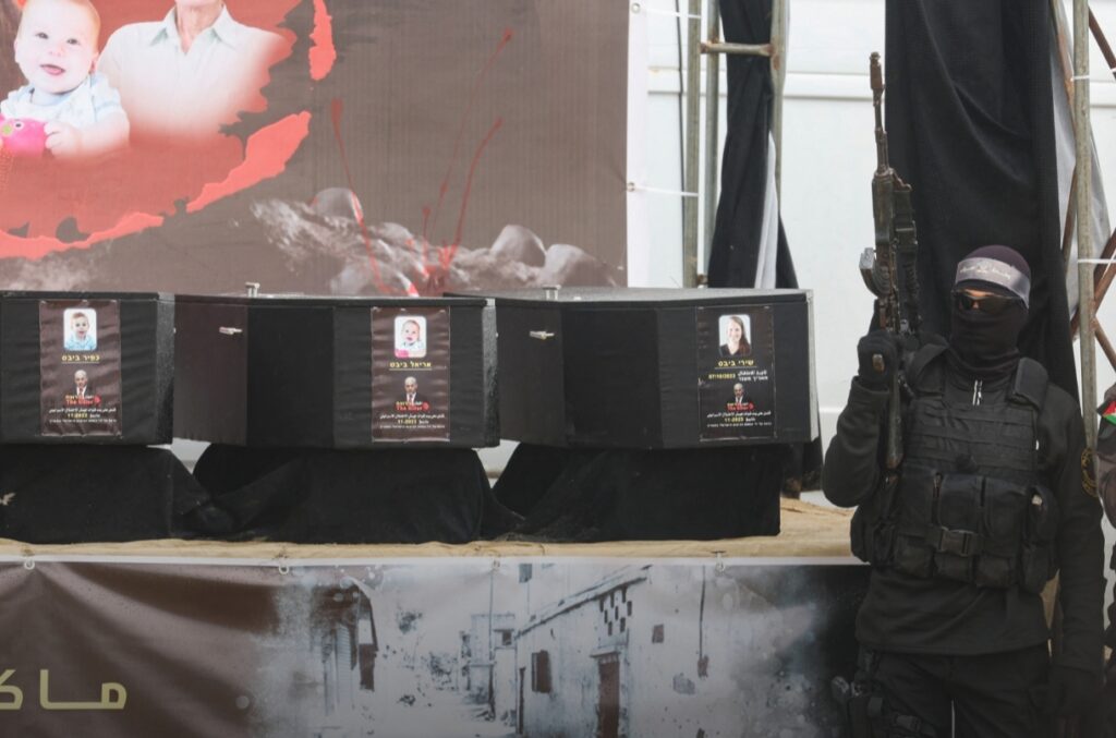 A Palestinian militant stands near coffins during the handover of deceased hostages in Khan Younis in the southern Gaza Strip, on Feb. 20, 2025.
